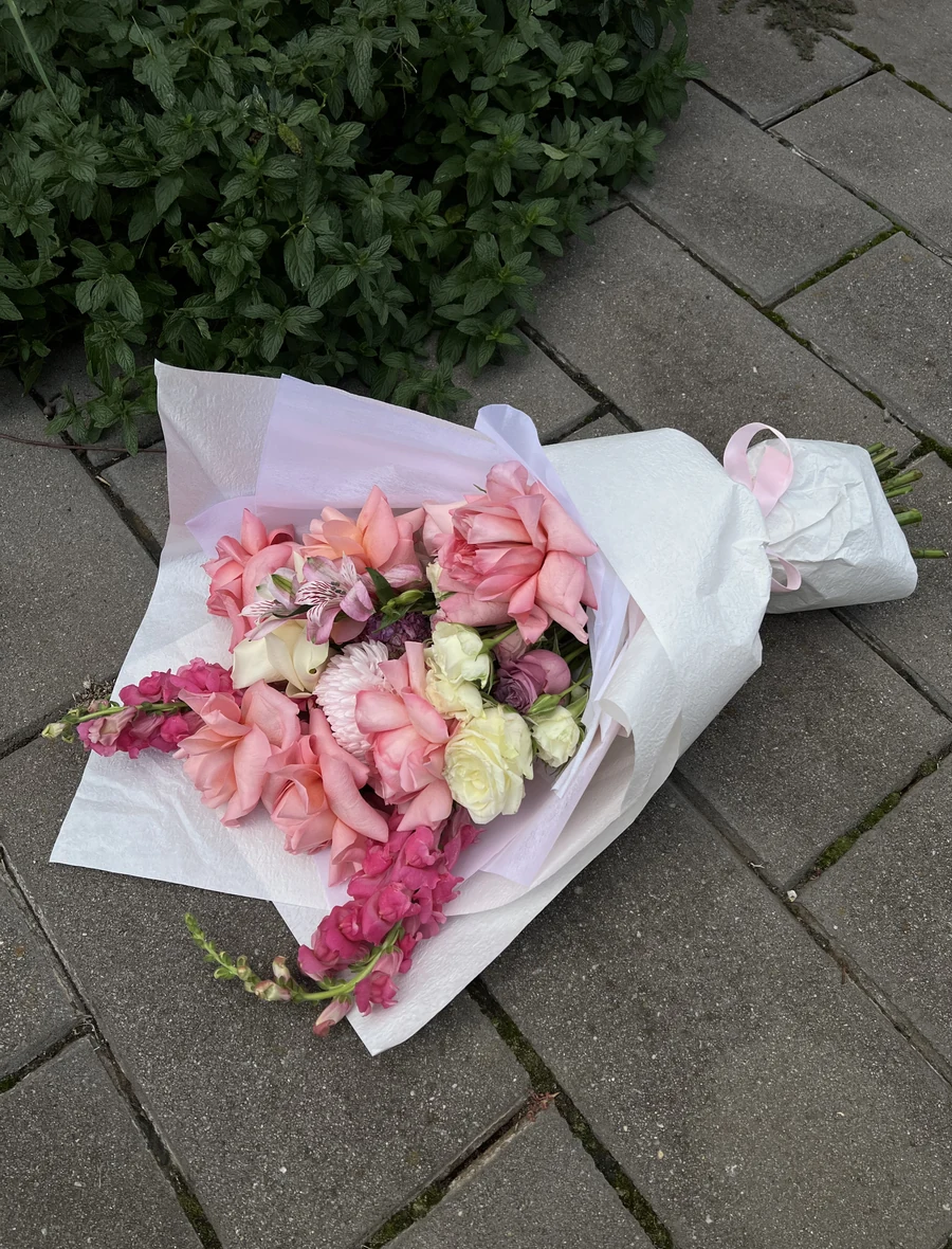 A pink Chirri Floral bouquet photographed from above on stone pavers.