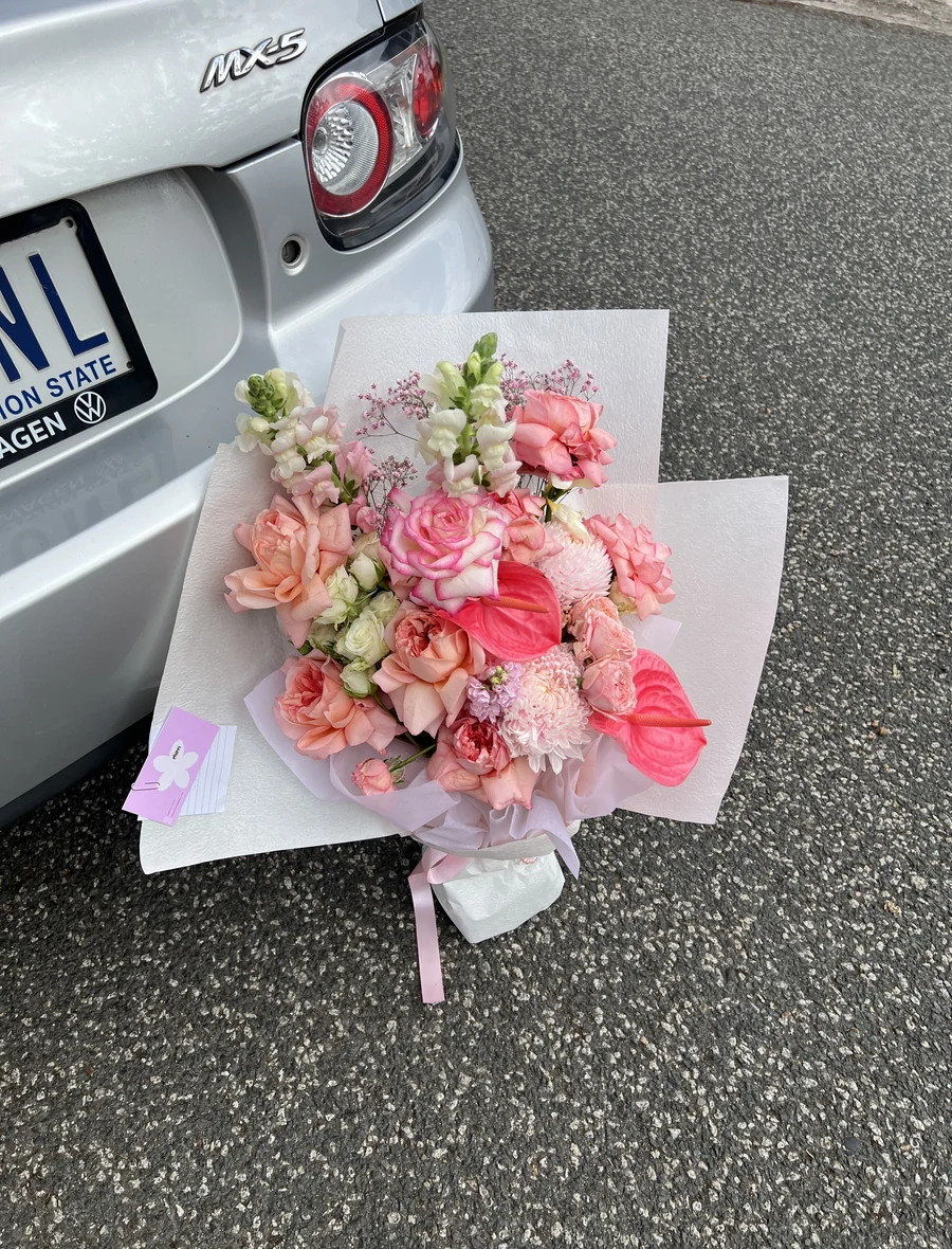 A Chirri Floral bouquet resting beside a car in natural light.