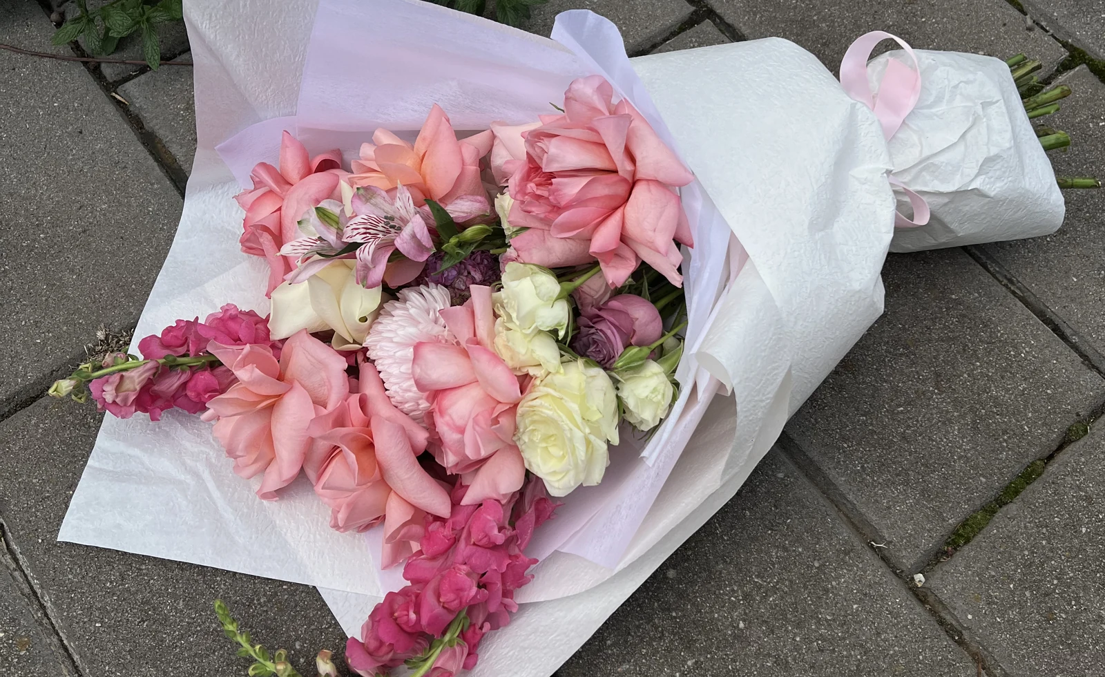 A pink and cream Chirri Floral bouquet wrapped in pale paper.